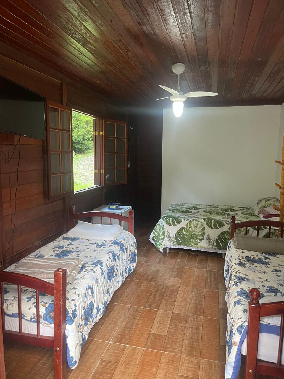 Interior da acomodação com TV e janela para o jardim